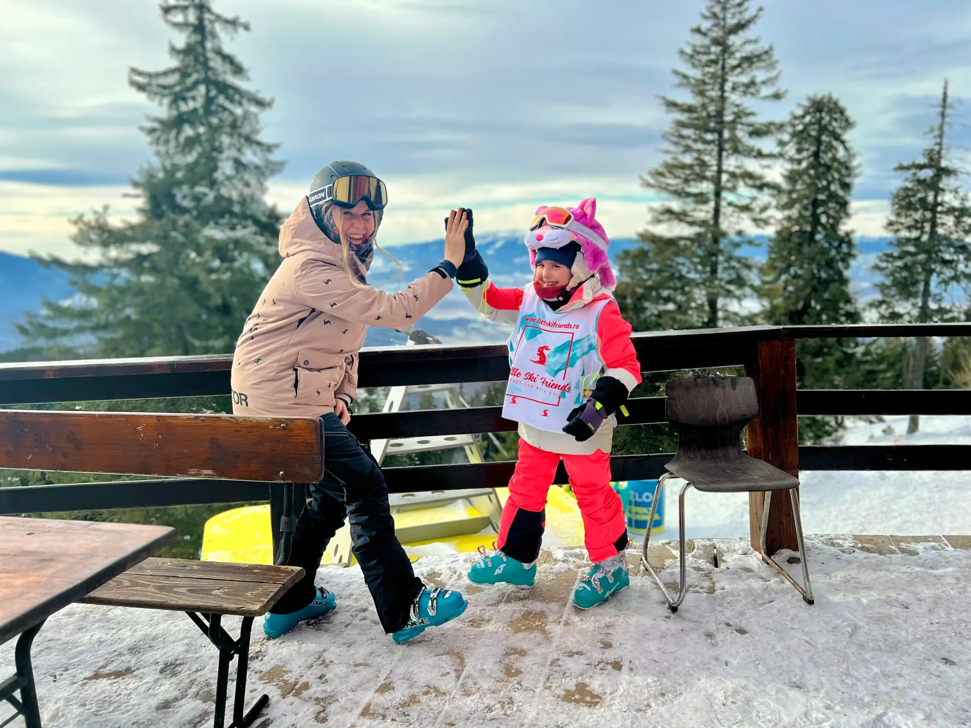 Instructor high-fiving a child in a ski lesson